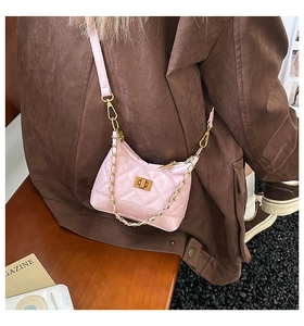 Detail of pink quilted crossbody bag with golden turn-lock and chain strap