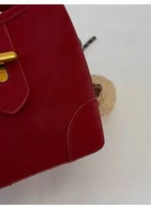 Gros plan du sac à main rouge texture litchi avec boucle métallique dorée élégante