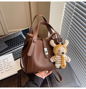 Détail du sac seau en cuir grainé marron avec un joli porte-clés ours en peluche