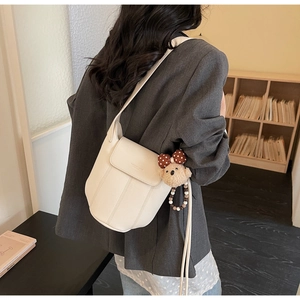 Detail of off-white lychee texture leather bucket bag with cute bear charm and beads
