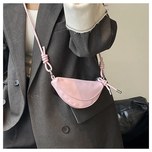 Sacoche rose en forme de croissant avec bandoulière nouée portée sur un blazer