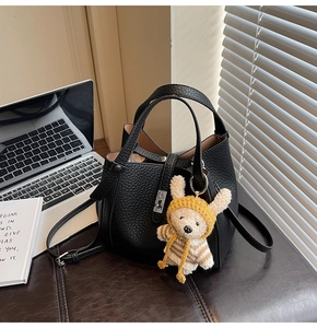 Détail du sac seau noir en cuir grainé avec charm ours et fermoir rotatif argenté