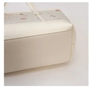Dettaglio di una grande borsa tote crema che mostra la grana della pelle e stampe di orsi