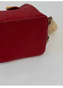 Gros plan sur la base large et stable de ce sac seau rouge en cuir grainé élégant
