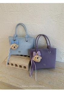 Detail of faux leather bucket bag with thick rope handles and plush dog charm