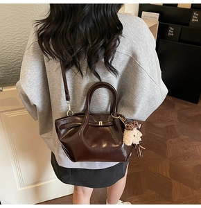 Détail du sac à main en cuir marron foncé avec un joli charme de chien en peluche