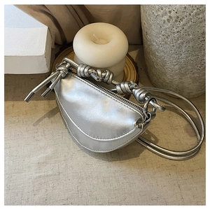 Détail du sac selle argenté montrant le similicuir texturé et la bandoulière nouée