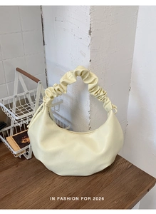 Detailed view of cream yellow pleated handbag with soft PU leather on wooden desk