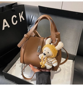 Détail d'un sac seau en cuir marron grainé avec boucle argentée et charm ours en peluche