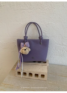 Detail of purple minimalist bucket bag with cute teddy bear charm and plaid bow decoration