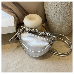 Détail du sac demi-lune argenté avec finition métallique et bandoulière à nœuds chic