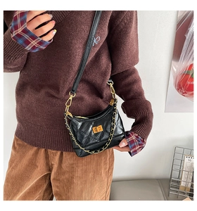 Detail of a black quilted crescent crossbody bag with gold chain strap and metal lock
