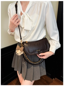 Detail view of brown retro baguette bag with gold chain and cute teddy bear charm