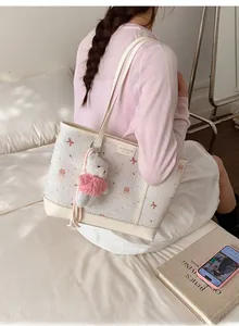 Dettaglio della borsa tote color crema con stampe e portachiavi a forma di orsetto
