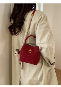Détail du sac seau en daim rouge avec fermoir doré et breloque ours sur le mannequin