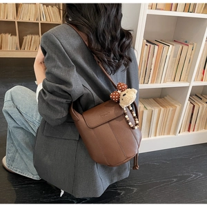 Detail of vintage brown pebble leather bucket bag with cute bear charm and bead straps