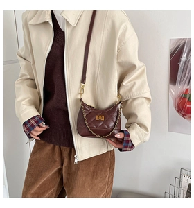 Close-up of a burgundy quilted mini crossbody bag with gold chain and twist-lock on a model