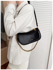 Detail of black leather bag with gold chain strap and brand logo on white background
