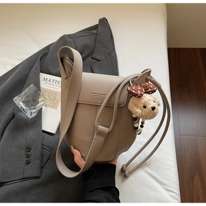 Detail of grey lychee leather bucket bag with puppy charm and fashion slogan engraving