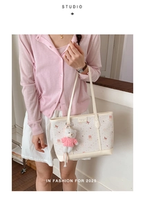 Dettaglio della borsa tote crema con fiocchi rosa e un ciondolo a forma di orsetto