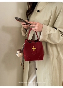 Détail du sac seau en cuir rouge avec fermoir doré et pendentif ours motif léopard