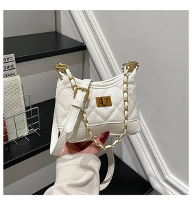 Detail of white quilted handbag with gold chain strap and metal turn-lock closure