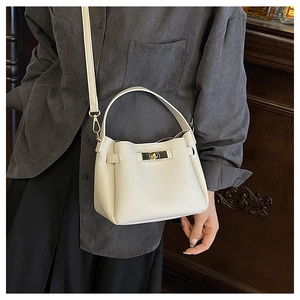 Détail du cuir grainé blanc et du fermoir pivotant en métal doré du sac seau