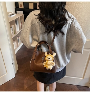 Détail du sac seau en cuir grainé marron foncé avec un joli pendentif ours