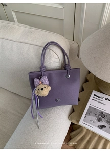 Detailed shot of purple frosted bucket bag with a cute plush bear charm in a cozy home setting