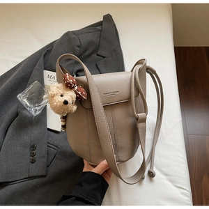 Detail of taupe pebbled leather crossbody bag with cute plush bear and bow charm