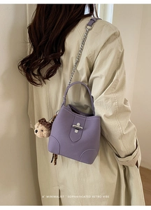Vue détaillée du sac seau violet avec chaîne argentée et breloque ours en peluche