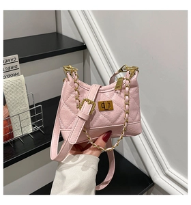 Detailed macro view of pink quilted handbag with gold chain strap and metal turn-lock