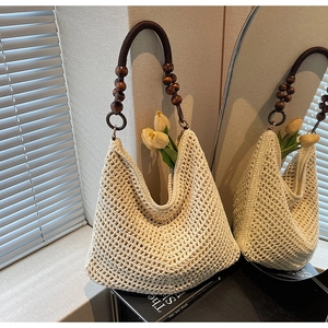 Detail of hollow knit hobo bag with unique brown wooden bead shoulder strap handle
