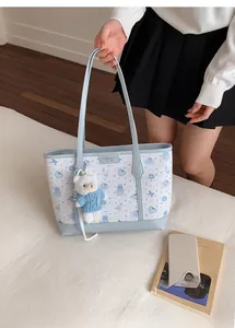 Dettaglio della borsa tote blu e bianca con motivi di orsi e un ciondolo di peluche
