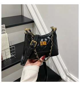 Close-up of black quilted shoulder bag with gold twist lock and glossy finish