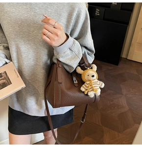 Détail d'un sac seau en cuir marron avec un joli pendentif en ours en peluche