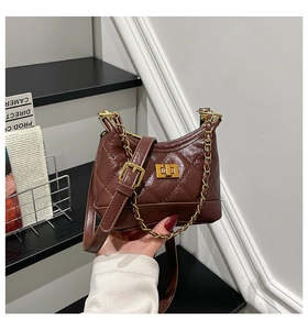 Close-up of brown quilted leather crossbody bag featuring gold clasp and chain strap detail