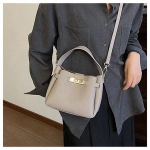 Détails du grain de cuir et du fermoir doré sur le sac seau gris clair élégant