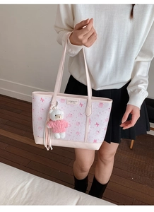 Dettaglio della borsa tote rosa e bianca con stampe di fiocchi e ciondolo orsetto