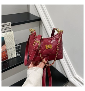 Detailed view of red quilted bag with gold metal clasp and chain strap craftsmanship