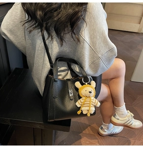 Vue détaillée du sac seau en cuir noir grainé avec un petit pendentif ours en peluche