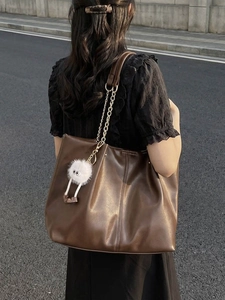 Large dark brown tote bag with metal chain strap and plush ball pendant for women