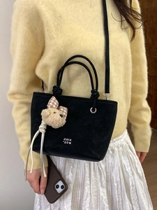 Chic black bucket bag with plush bear charm and crossbody strap for spring fashion