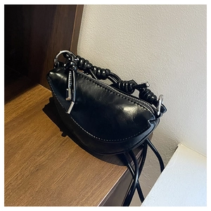 Détail du sac demi-lune noir avec poignée nouée et finitions métalliques argentées