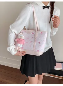 Dettaglio borsa shopper rosa con stampe di gatti e ciondolo orsetto sulla spalla della modella