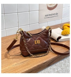 Detail of a dark brown quilted shoulder bag with gold twist-lock and chain strap