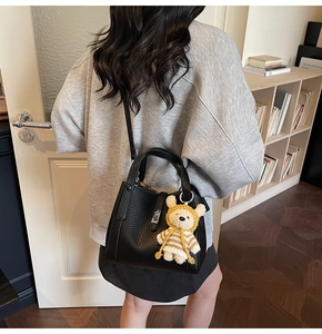 Détail du sac seau noir en cuir grainé avec un pendentif ours en peluche au crochet