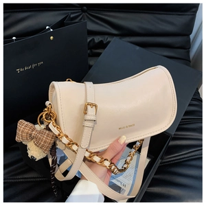 Detail of cream leather crescent bag with gold logo, chain strap and cute bear charm