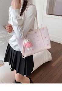 Dettaglio della borsa tote rosa con illustrazioni di conigli e ciondolo orsetto