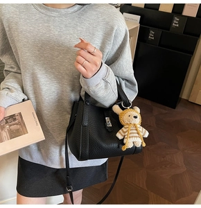 Détail du sac seau en cuir grainé noir avec ferrures argentées et breloque ours mignon